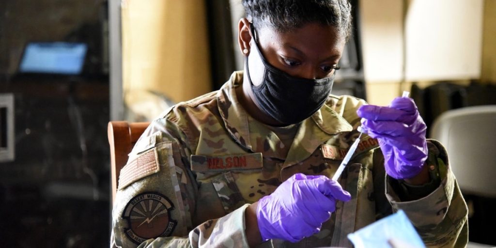 Sgt. Suzanne Nelson of the Arizona National Guard fills a syringe with the COVID-19 vaccination. Photo by Flickr user thenationalguard.